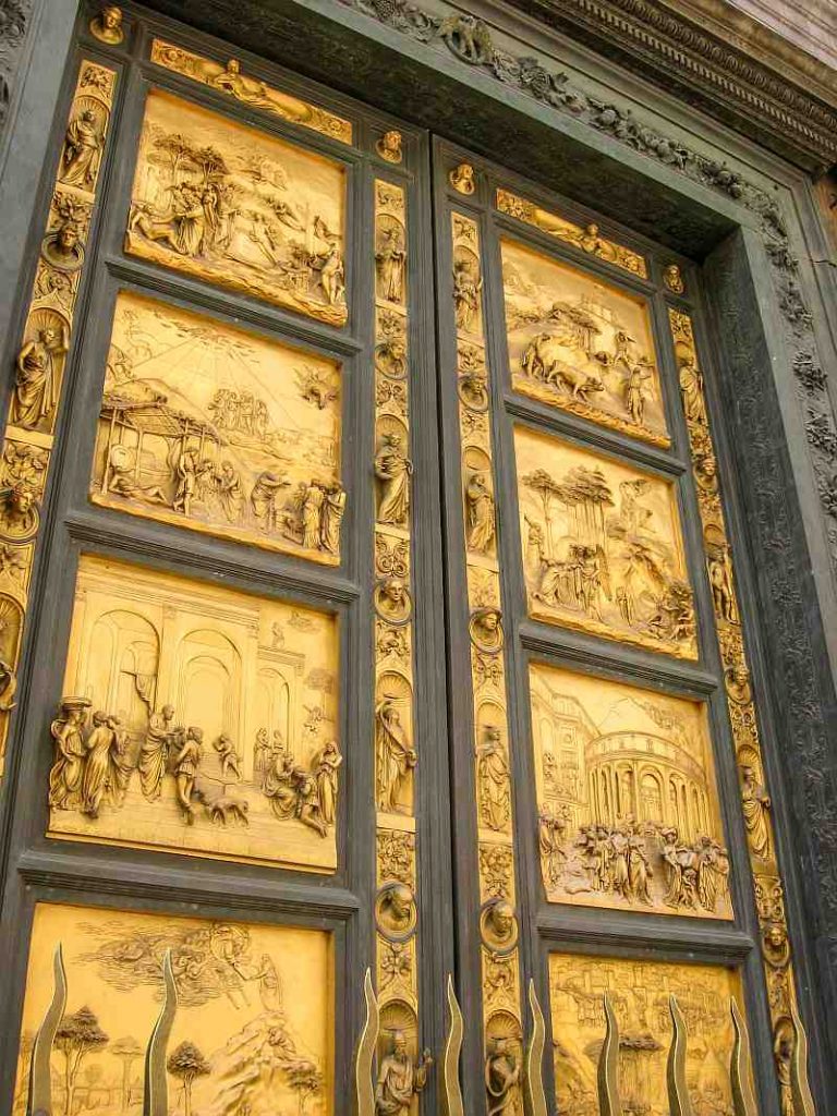 Tall bronze doors with gold panels featuring intricate reliefs depicting various biblical scenes. The borders are dark and ornate, and the artwork is detailed and three-dimensional. Gates of Paradise on the Baptistery in Florence