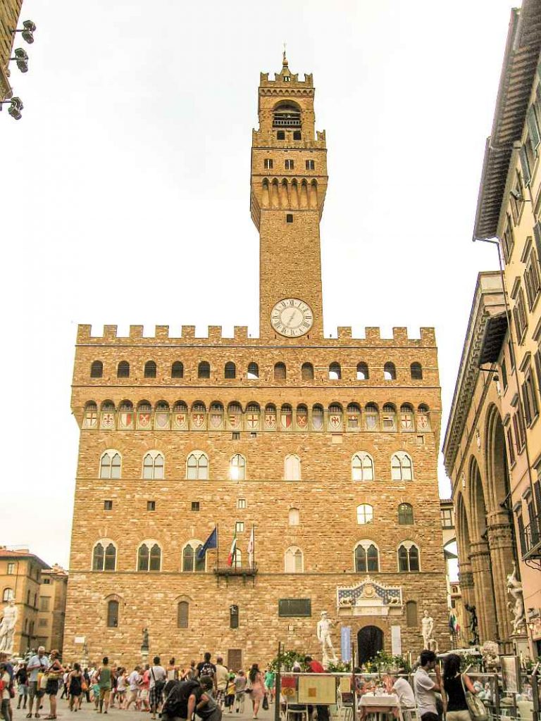 Palazzo Vecchio in Florence with the clock tower at sunset and lots of people on the square in front