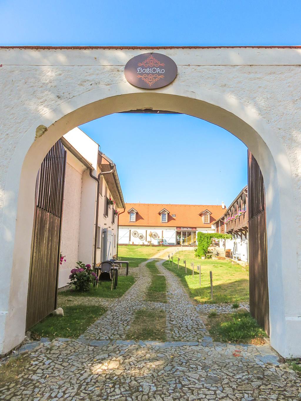 a cobbled stone path leading through and open gate to an inside yard; Male Chrastany South Bohemia