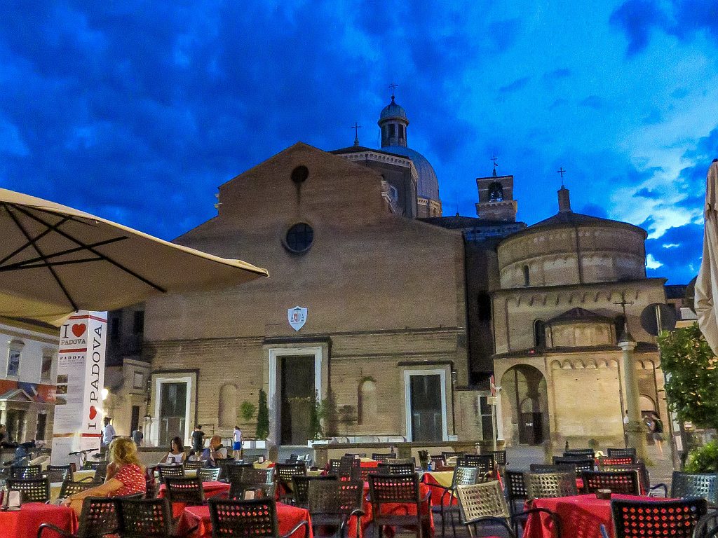 a church with a plain facade and a restaurant in front of it and a sign I love Padua, Il Duomo Cathedral in Padua