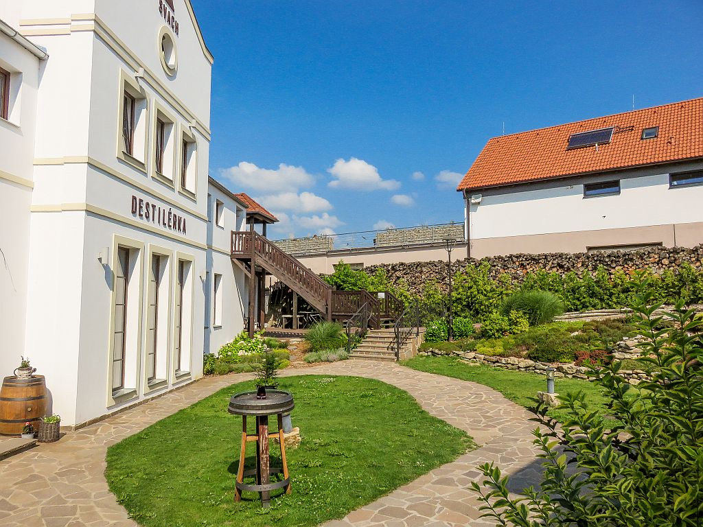 inner court with a white building and some green landscaping; the distillery of the Svachovka Complex