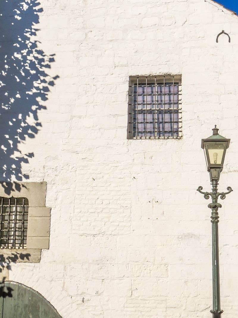a whitewashed outer wall of a house with a bricked-up window and the beautiful lamp post in front of it, Thorn Netherlands