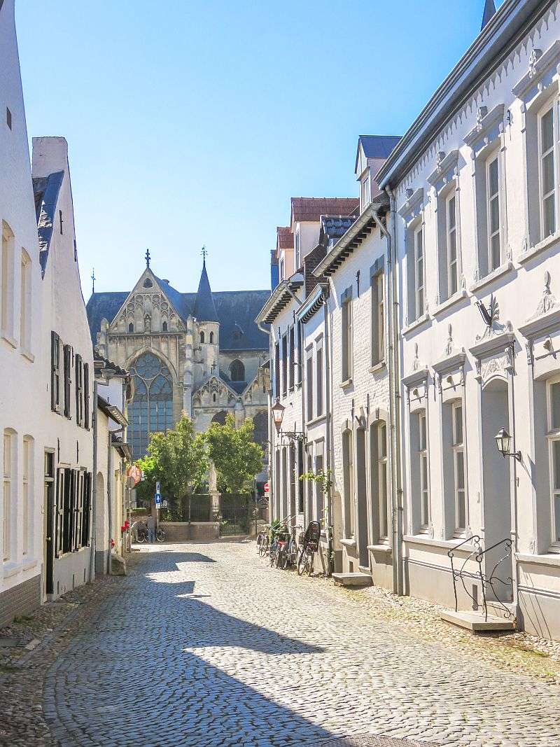 a cobblestone street lined up with whitewashed houses with a church at the end of the street, Thorn, Middle-Limburg, The Netherlands