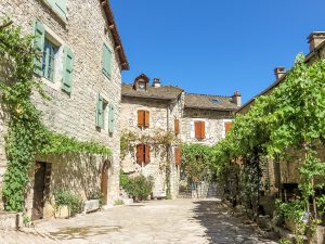 stone houses on a small square with vines hanging above the sidewalk, summer destination in europe