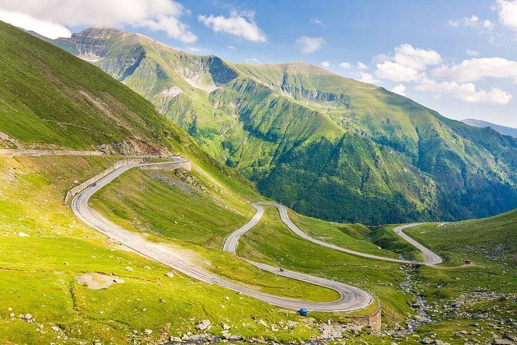 a winding road with hairpin bends in a green mountain, the Transfagarasan mountain road in Romania