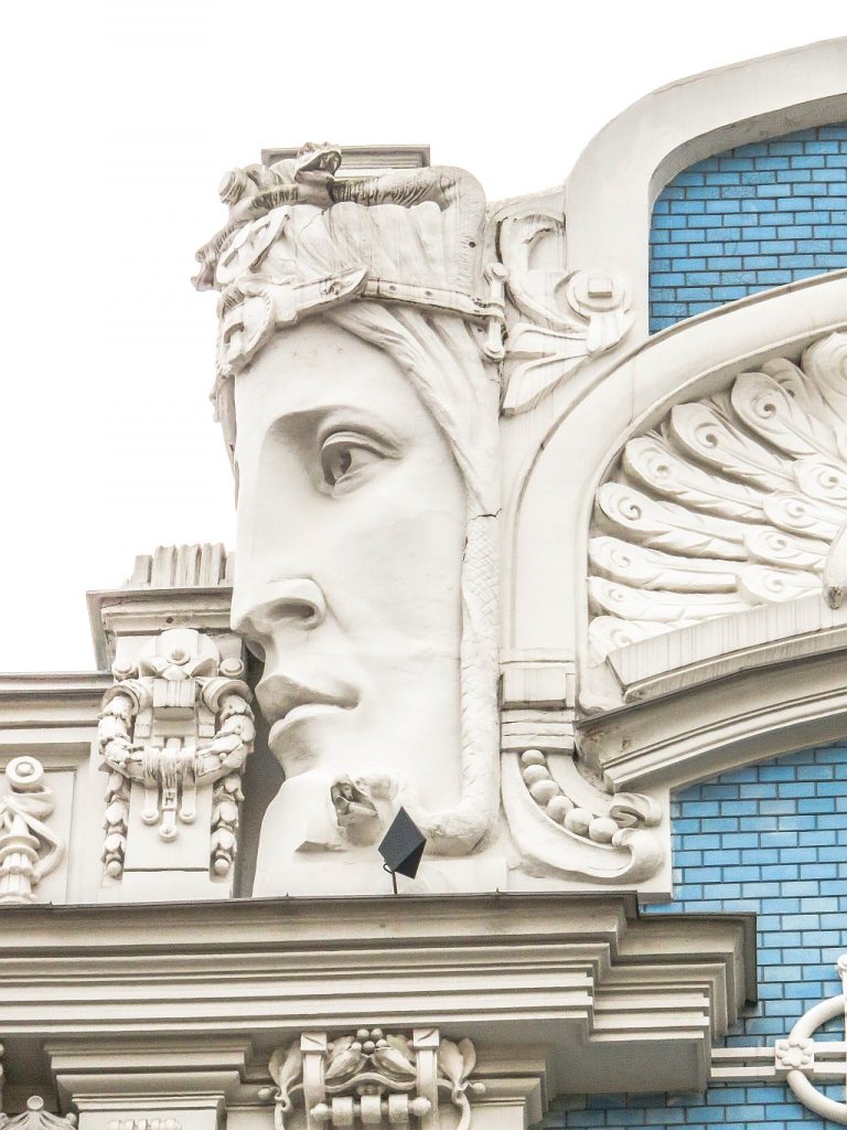 a large head with ornaments on a facade of a building in Riga