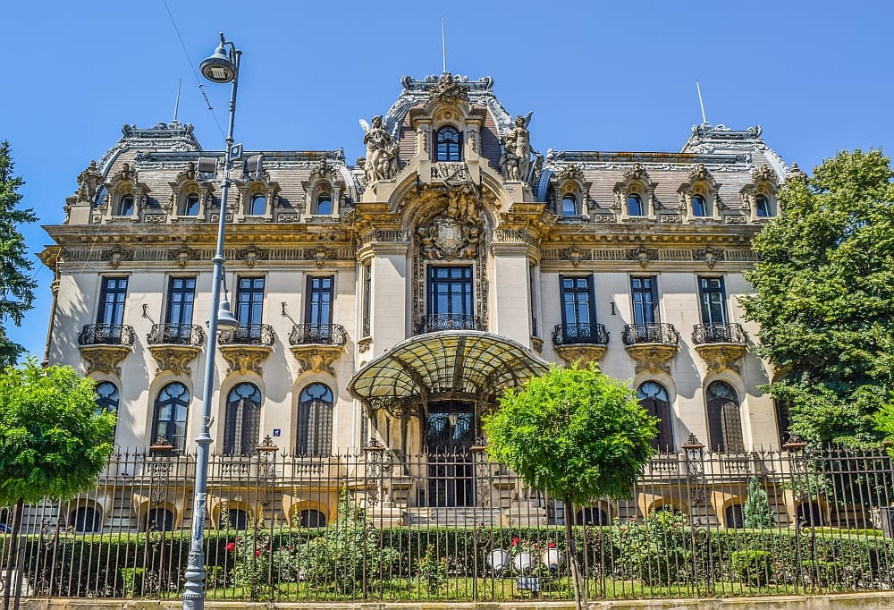 a beautiful building with a lot of ornaments and a sea-shell shaped roof above the entrance, the Cantacuzino Palace in Bucharest