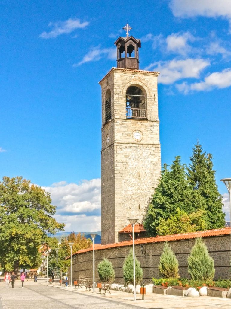 a tall clock tower with bells and a cross on top , the Clock tower in Bansko