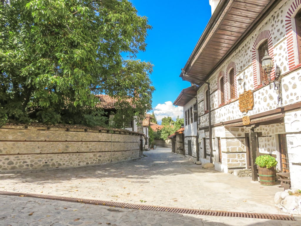 a cobbled street lined up with traditional houses yards with high stone walls; a street in the Old Town in Bansko