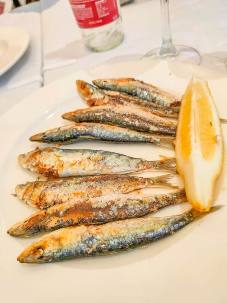8 bbq-ed sardines with a piece of lemon on a plate