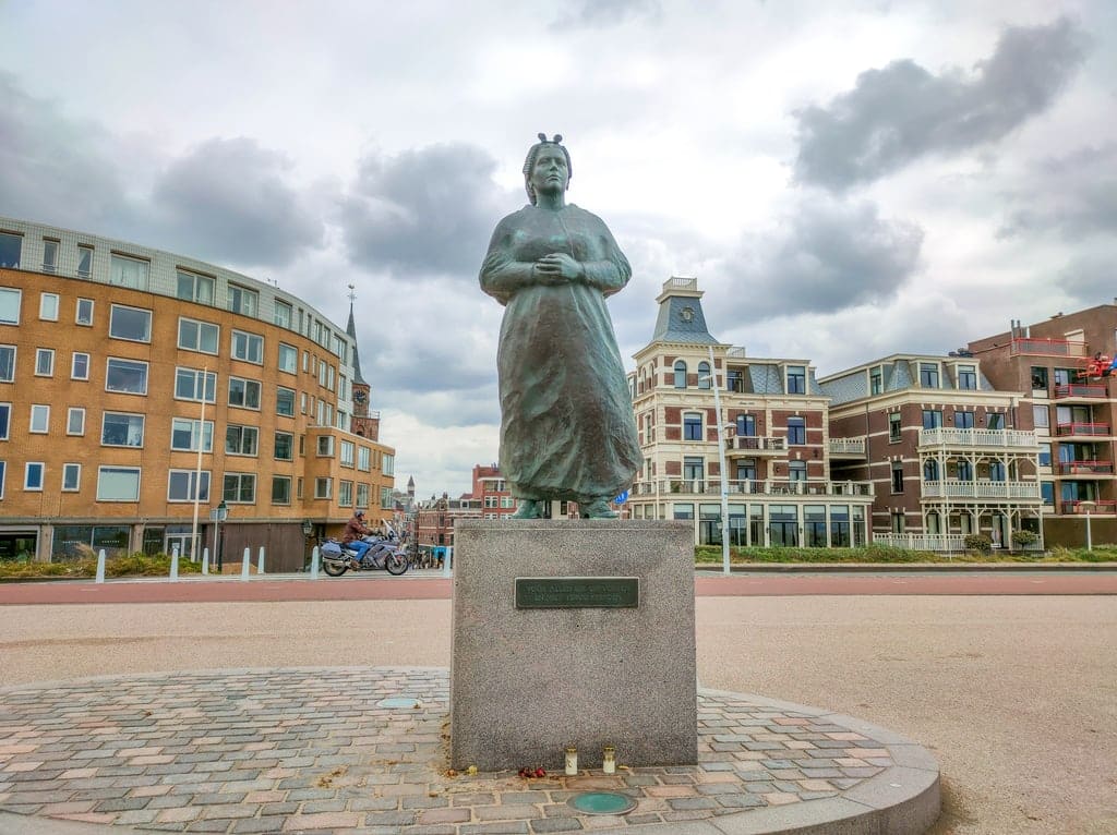 a monument of a woman standing on the pier and looking into the sea; The Fisherman's Wife in Scheveningen