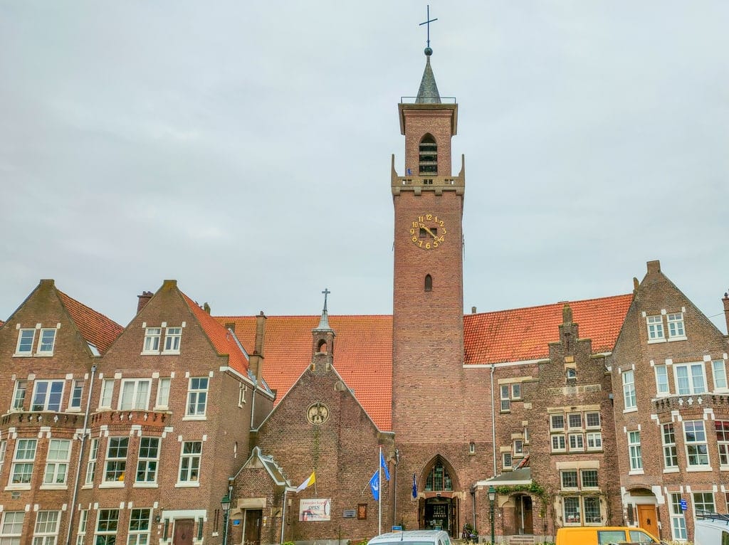 a church in the middle of a row with houses; Our Lady of Lourdes Chapel in Scheveningen