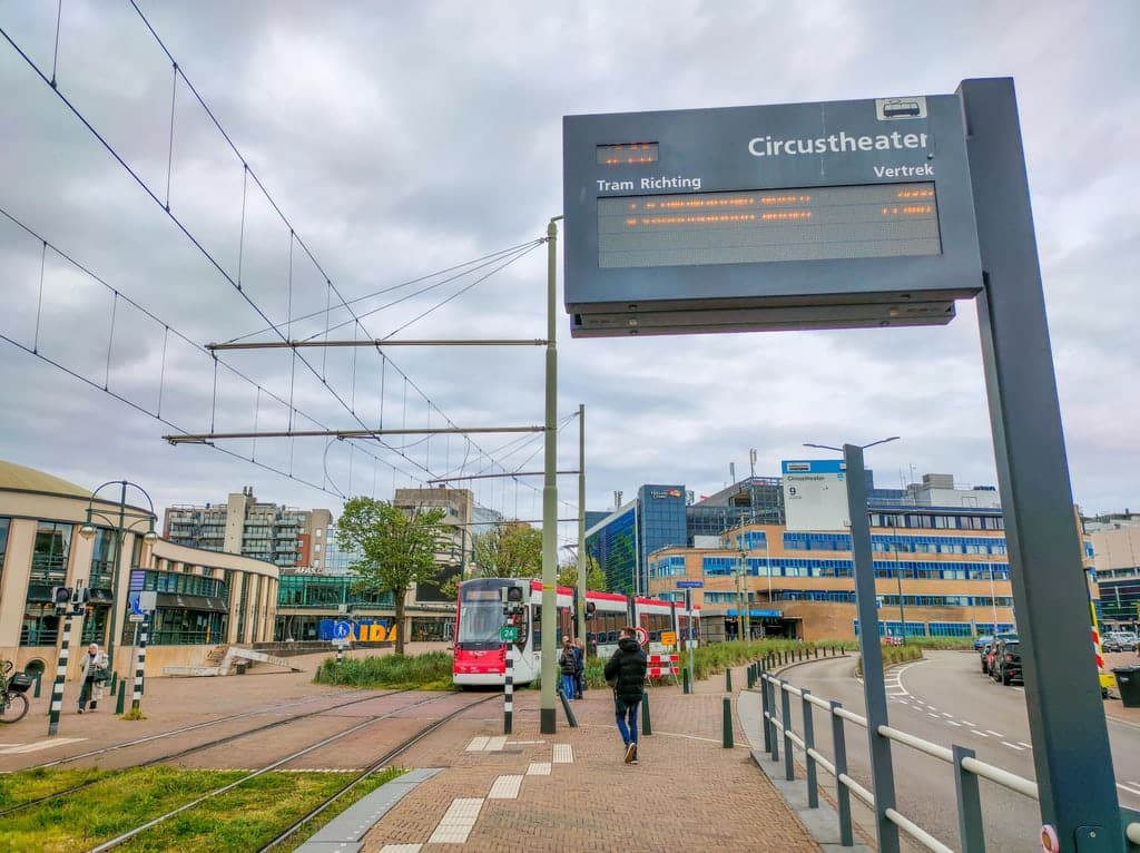 a red and white tram in Scheveningen approaching a tram station