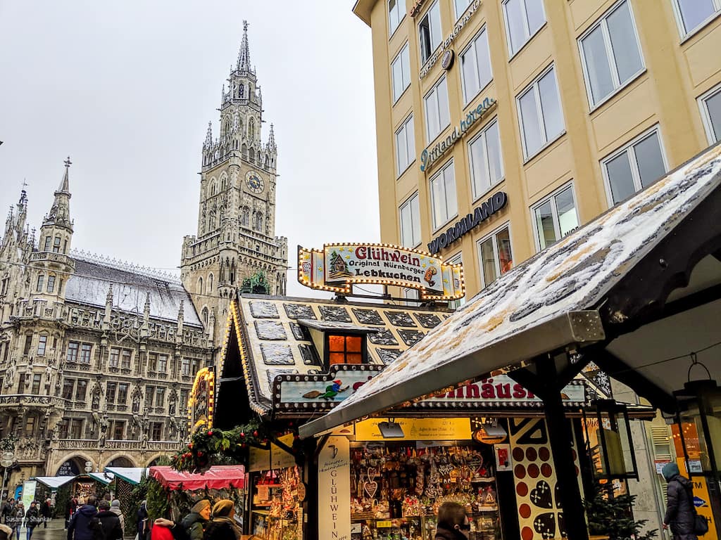 Christmas markets stall decorated with twinkling lights and a beautiful Gothic building with a tower clock as a backdrop, Christmas market in Munich, Germany